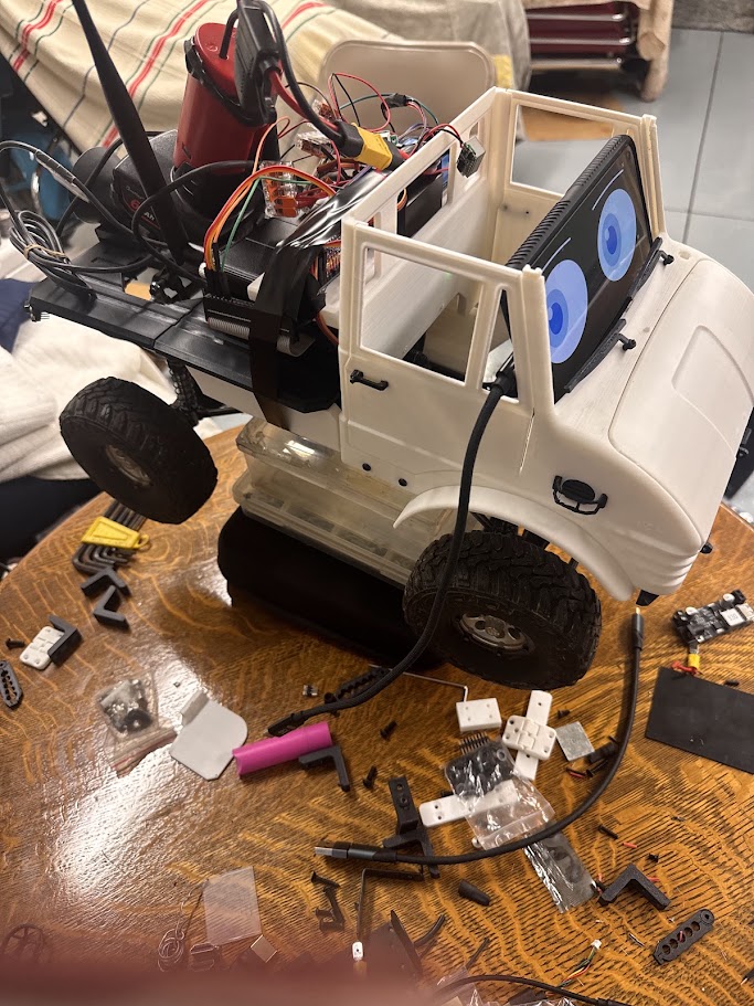 The Kilo rover mid-assembly on a workbench, surrounded by 3D-printed brackets, fasteners, wiring and tools